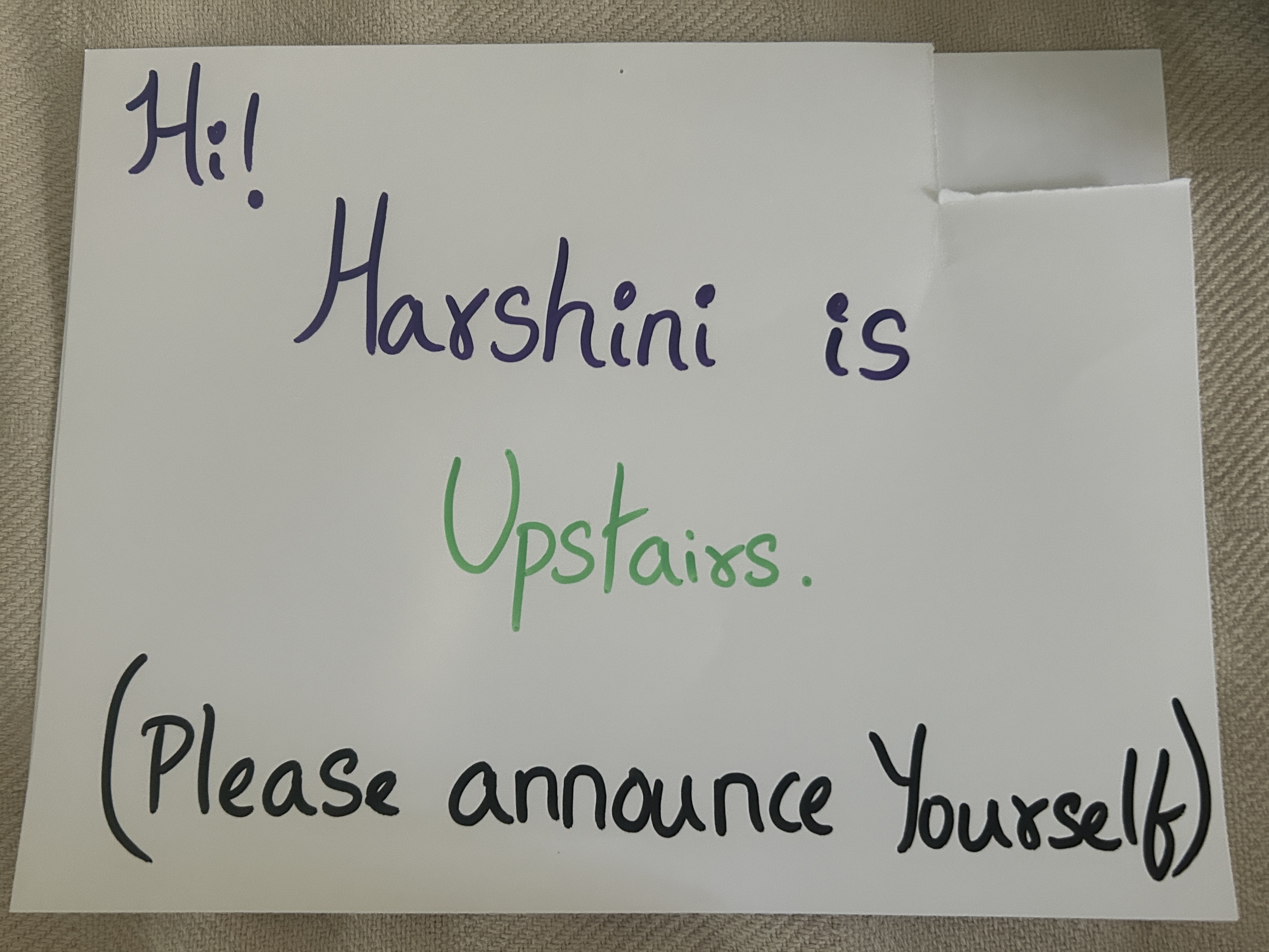 A handwritten door sign reading "Hi! Harshini is Upstairs. (Please announce yourself)" in purple, green, and black marker.