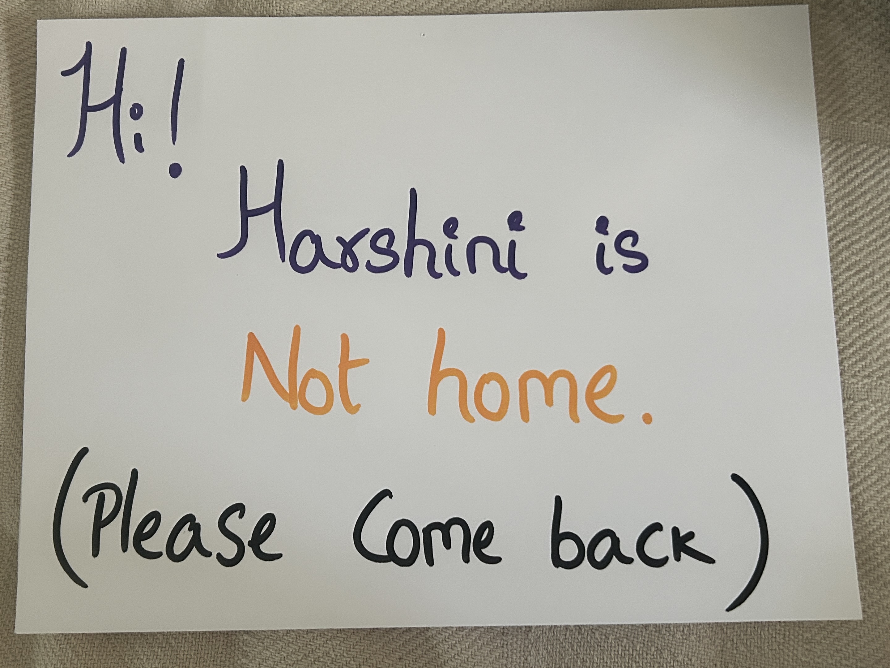 A handwritten door sign reading "Hi! Harshini is Not home. (Please Come back)" in purple, orange, and black marker.